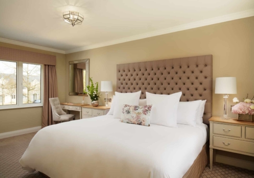 A sophisticated bedroom with a large bed, plush armchair, elegant chandelier, and soft lighting, creating a luxurious and inviting atmosphere.