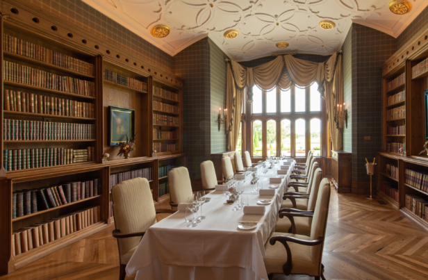 Elegant private dining room at Adare Manor with plush seating, ornate bookshelves, and set dining table for a Krug Champagne event, showcasing luxury and sophistication.